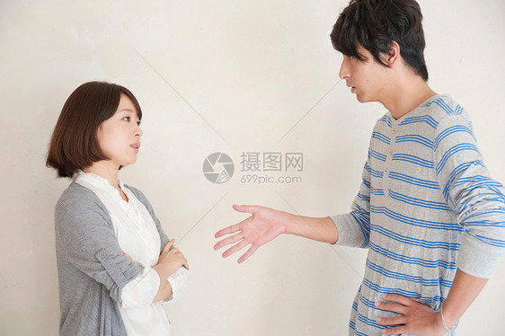 亚洲夫妻吵架：发怒的双人撅嘴，白墙见证愤怒图片