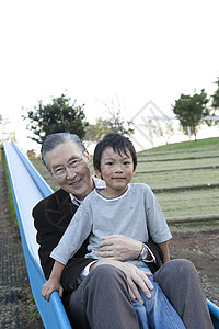 公园玩滑滑梯的老人和孙子图片