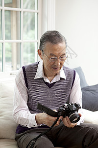 客厅沙发上研究相机的老年男性图片