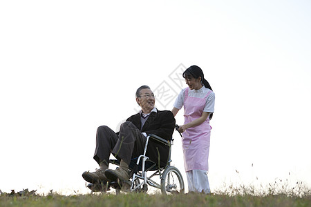 护理看护推着轮椅上的老年人散步图片