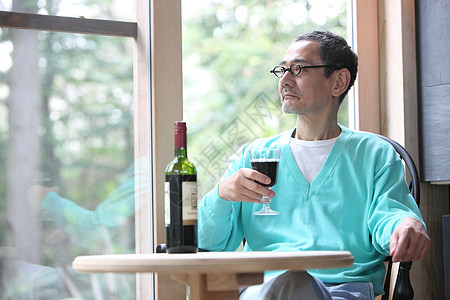 中老年男子坐在窗边喝葡萄酒红酒图片