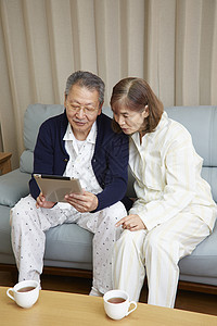 老年夫妇在客厅里查看平板电脑图片