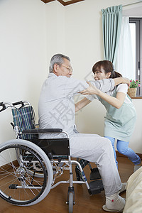 护工扶老人坐上轮椅图片