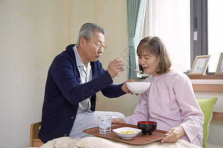 老年男性在喂妻子吃饭图片