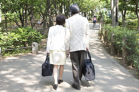 户外拎着包散步的中年夫妇背影图片
