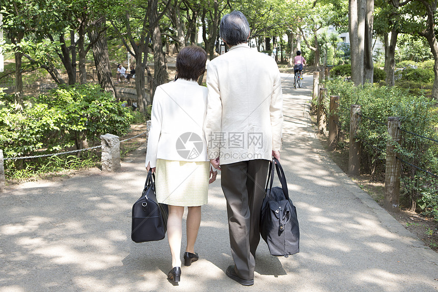 户外拎着包散步的中年夫妇背影图片