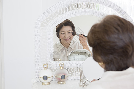 中老年女性在镜子前化妆图片