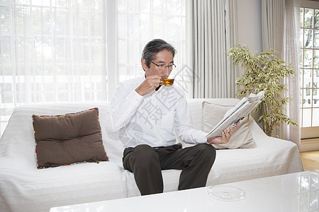 中年男性在沙发上喝茶看报纸图片