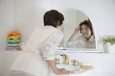老年女性镜子前查看脸上的皱纹图片