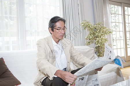 客厅沙发上的中老年男性看报纸图片