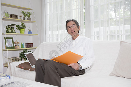 客厅沙发上的中老年男性居家办公图片