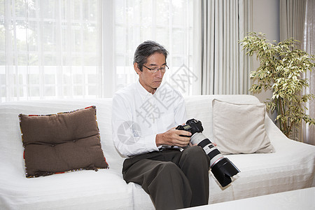 在沙发上使用相机的中年男性图片