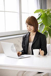 笔记本电脑前喝咖啡的女人图片
