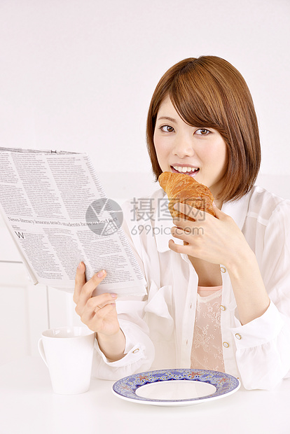 吃早餐面包看报纸的妇女图片