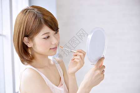 照镜子化妆的年轻女人图片