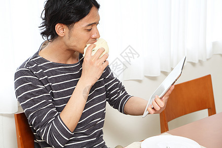 看着平板电脑吃早饭的青年男性图片