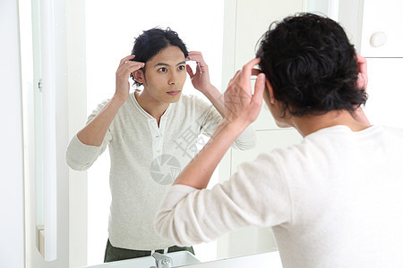 男人在对着镜子整理头发图片