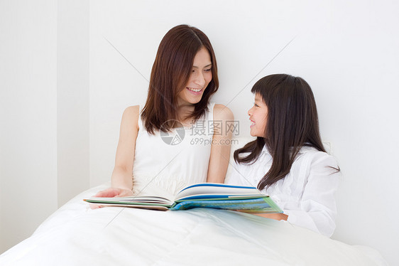 母亲和小女孩在餐桌上看书图片
