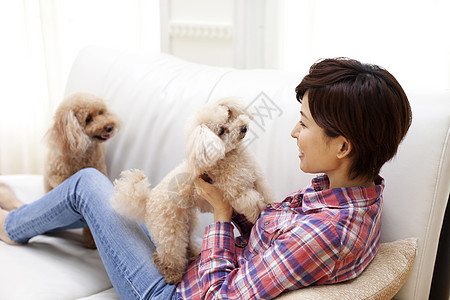 女性和狗狗在沙发上玩耍图片