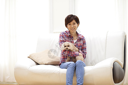 女性抱着狗狗坐在沙发上图片
