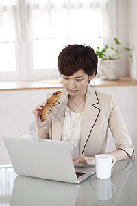在家工作吃面包的女性图片