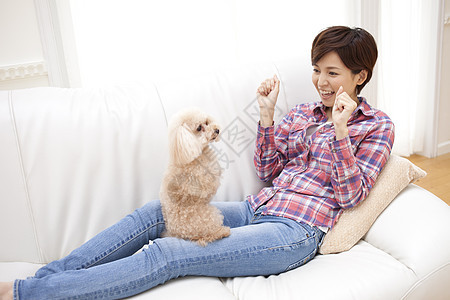 沙发上跟宠物狗玩耍的女主人图片
