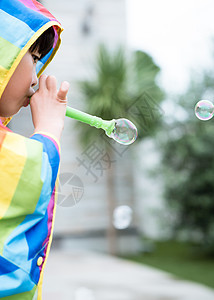 穿彩色雨衣的小朋友吹泡泡图片