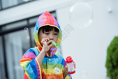 穿彩色雨衣的小男孩吹泡泡图片