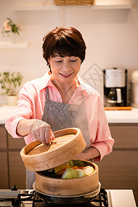 厨房里蒸食材的老年女性图片