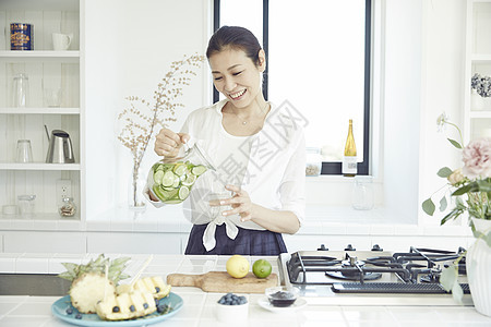 漂亮主妇在明亮的厨房里制作饮品图片