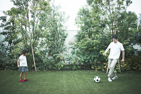 在户外草坪上踢球的父女图片