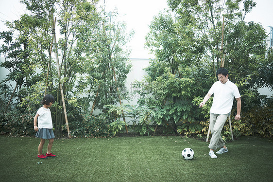 在户外草坪上踢球的父女图片
