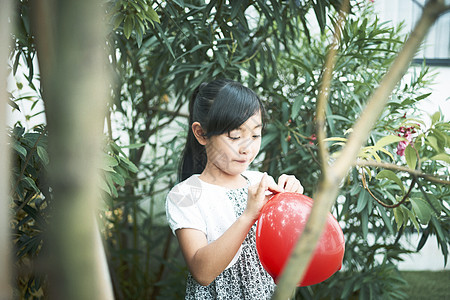 小女孩在花园里吹气球图片