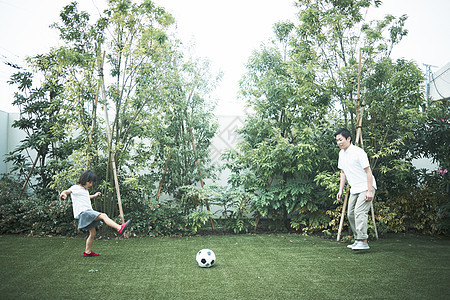 室外花园里踢球玩耍的父女图片