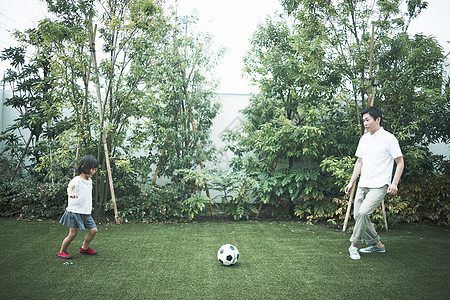 室外花园里踢球的父女图片