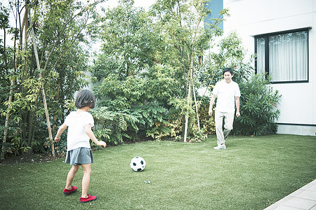 家长陪孩子花园里踢球图片