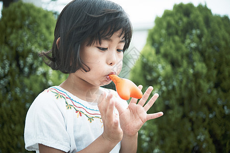 小女孩在花园里吹气球图片