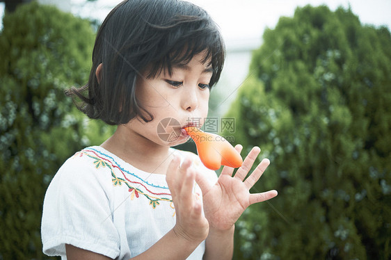 小女孩在花园里吹气球图片