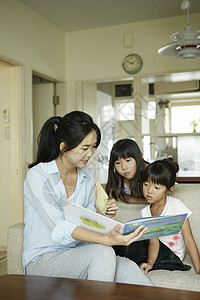 居家的母亲陪伴孩子看图画书图片