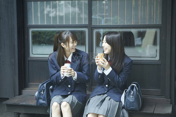 坐在长椅上吃早点的女高中生图片
