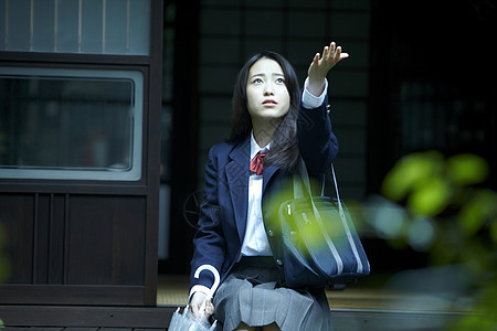 雨天从房屋外伸出手的女孩图片