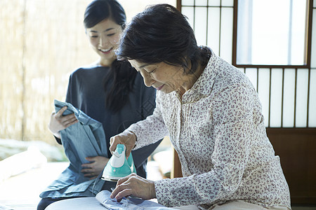 女儿和母亲在熨烫衣服图片