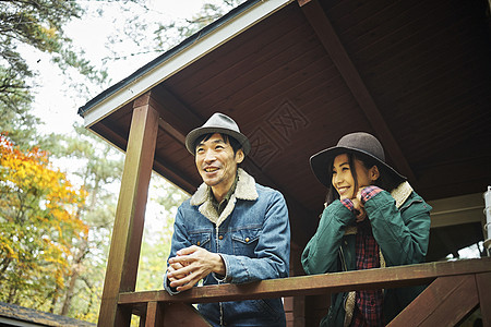 树林野营地外在小屋里放松的情侣图片