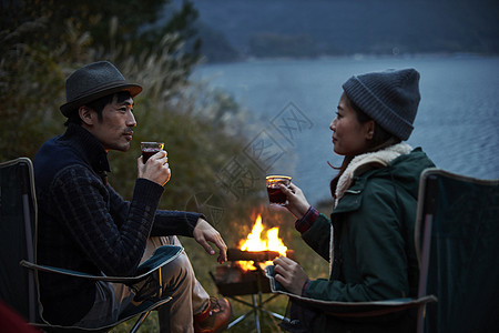 野营夫妇在篝火前喝咖啡图片