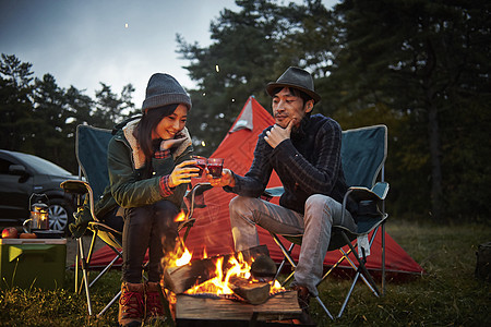 篝火前取暖休闲的野营男女图片