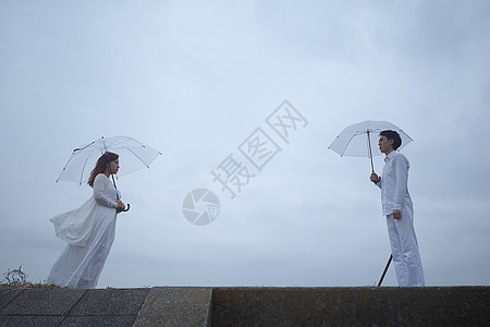 岸上撑伞的浪漫情侣图片