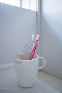 盥洗室卫生间里的牙刷和杯子图片