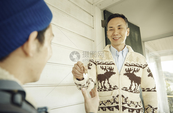 站在入口处递钥匙的男性图片