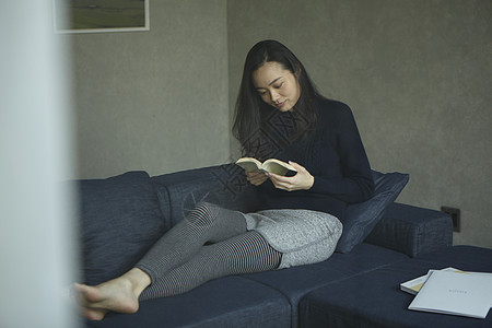 坐在沙发上看书的年轻女子图片