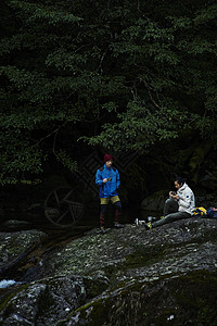 山林中旅行的两个男背包客在溪边休息图片